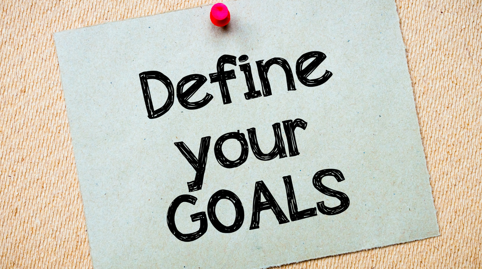 The phrase ‘Define your goal’ written on a grey cardboard, symbolizing the importance of setting clear objectives in video marketing for beginners.