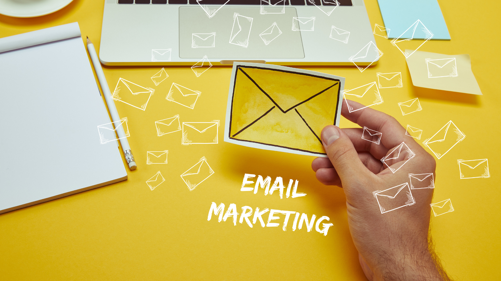 cropped image of man holding envelope near laptop with "Email Marketing" lettering and email icon